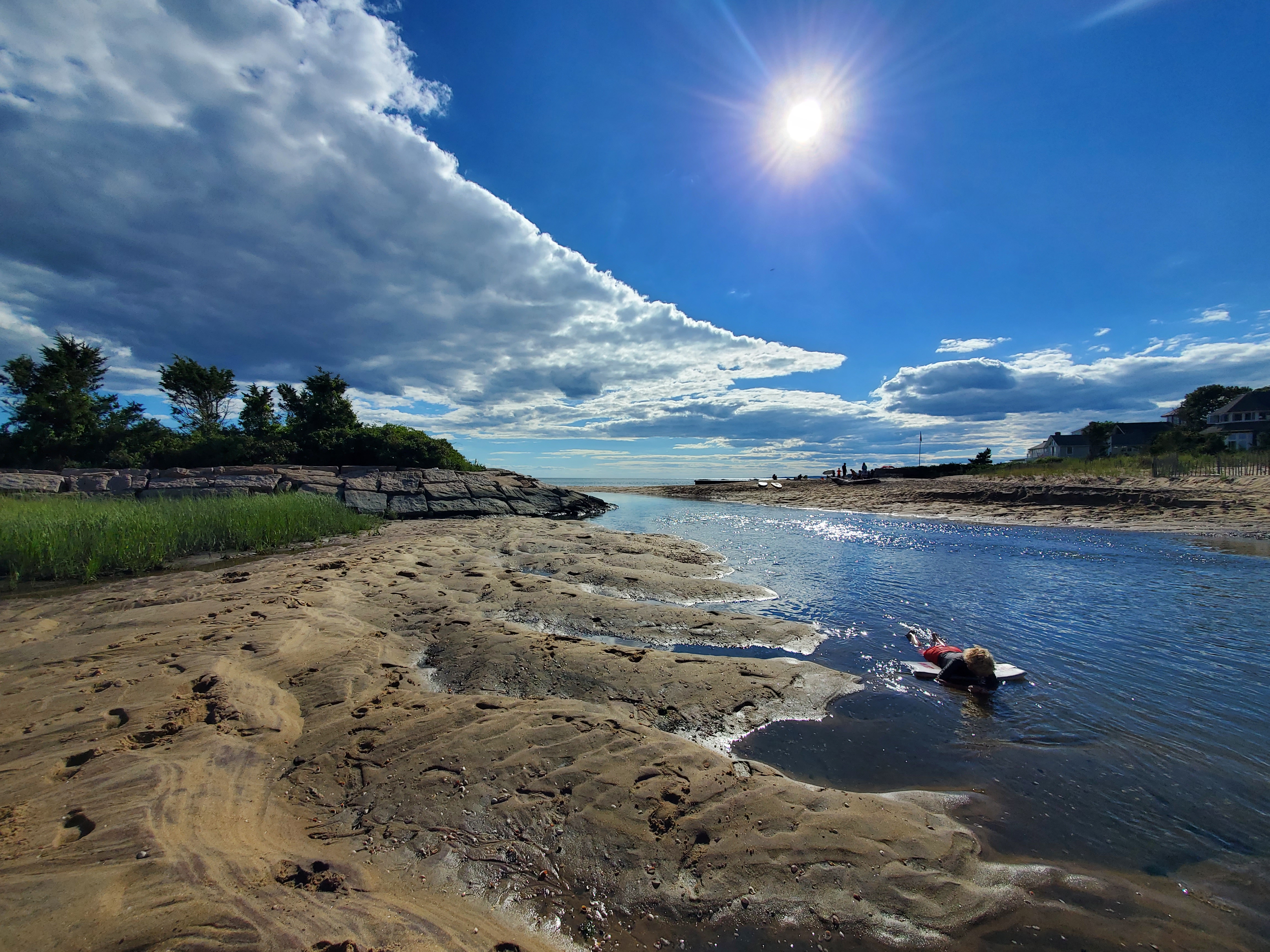 Connecticut creek that lets out into the ocean coastline with sun in background